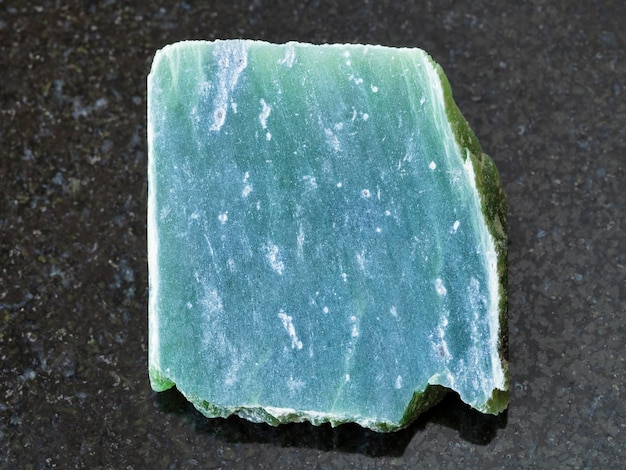 Raw nephrite stone slab on dark background