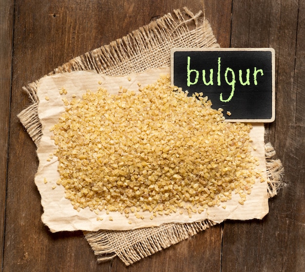 Raw organic bulgur with a chalkboard on a wooden table top view