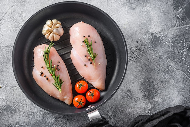 Raw organic chicken breastin grill pan on a grey background. Food preparation, top view.