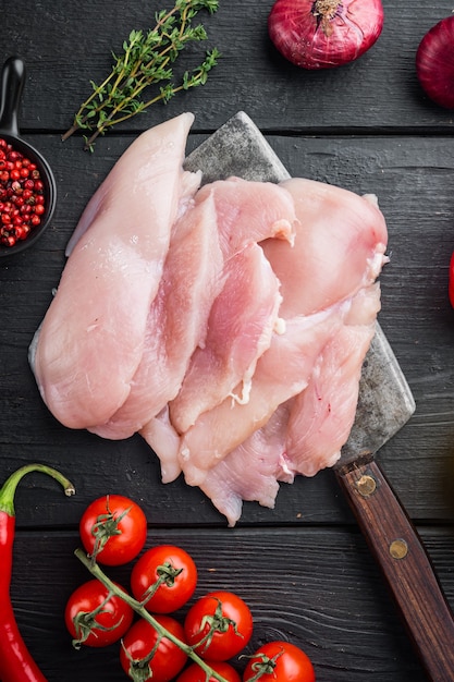 Raw organic chicken breasts, on black wooden table table, top view flat lay