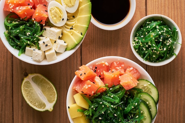 Raw Organic Poke Bowl with with rice, avocado, salmon, on wooden background top view