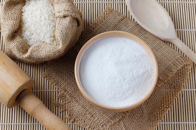 Raw organic rice flour in bowl over rustic wooden table gluten free food