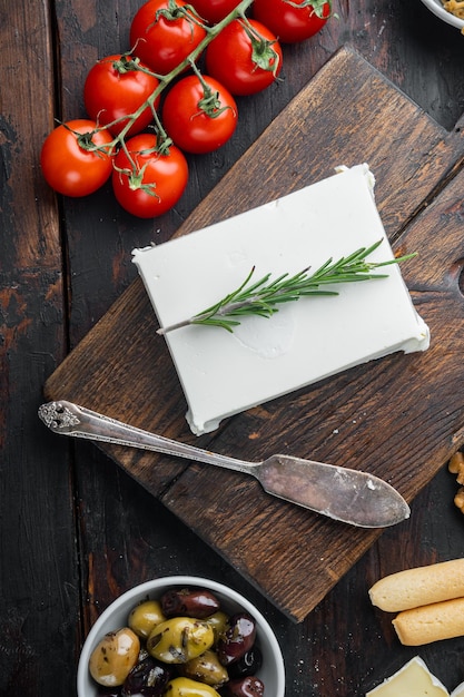 Raw organic white feta cheese on dark wooden background flat lay