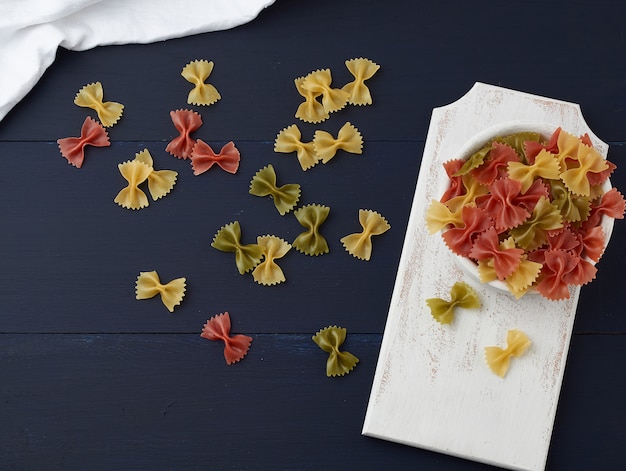 Raw pasta in the form of bows in a wooden round plate