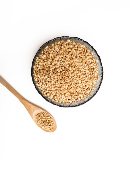 Raw pearl barley in a wooden spoon and in a plate