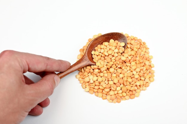 Raw peas on a wooden spoon on an isolated space