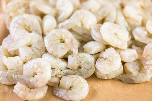 Raw peeled shrimp on a brown butcher paper.