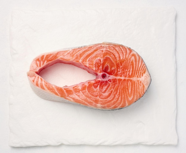 Raw piece of salmon on a white board top view