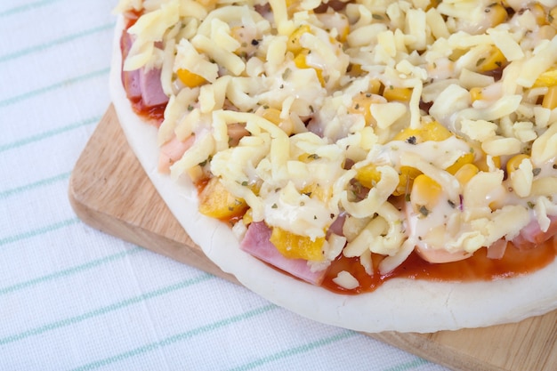 Raw pizza on wooden board on the table with top view