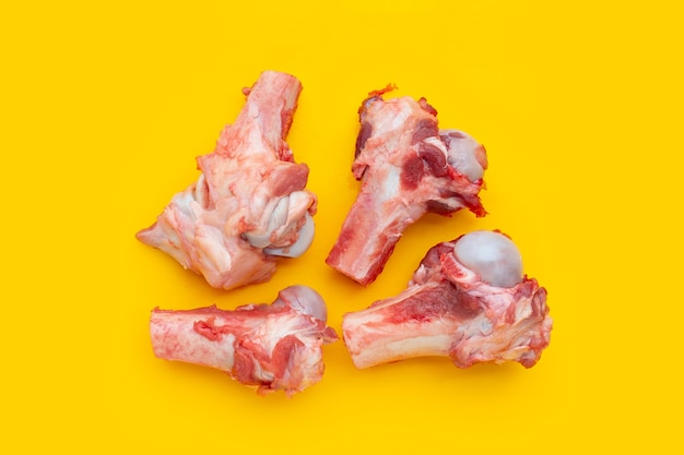 Raw pork bones on yellow background.