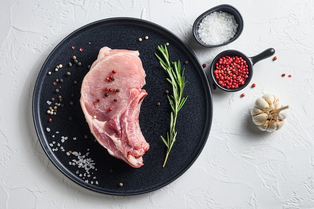 Raw pork chop in a black round plate