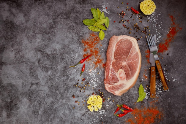 Raw pork chops with spices on dark background