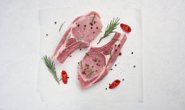 Raw pork loin on the bone with spices on a white background Portion for lunch and dinner viewed from the top