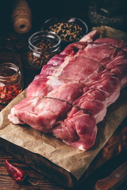 Raw pork loin joint on cutting board with different spices