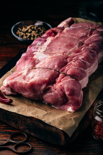 Raw pork loin joint on cutting board with different spices