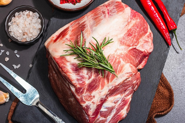 Raw pork loin with spices and herbs Fresh meat cut ingredient for cooking protein food healthy food lifestyle Trendy hard light dark shadow black stone concrete background top view