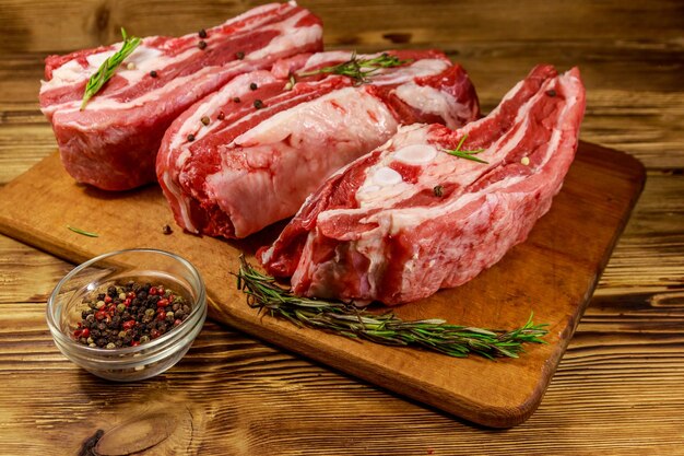 Raw pork ribs with spices and rosemary on wooden table