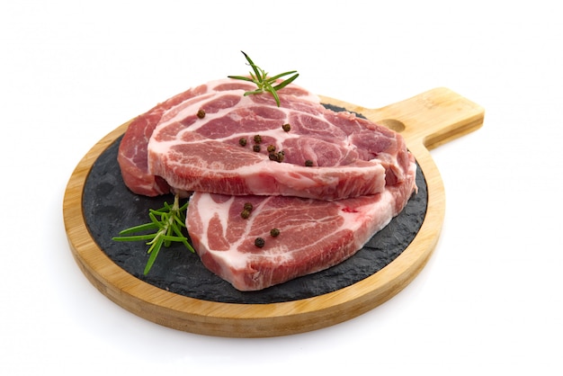 Raw pork slices on black stone plate, isolated on white.