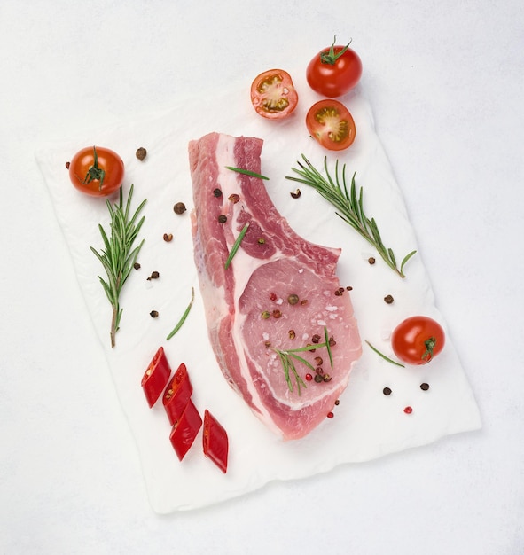 Raw pork tenderloin on the bone and spices on a white background Portion for lunch and dinner top view