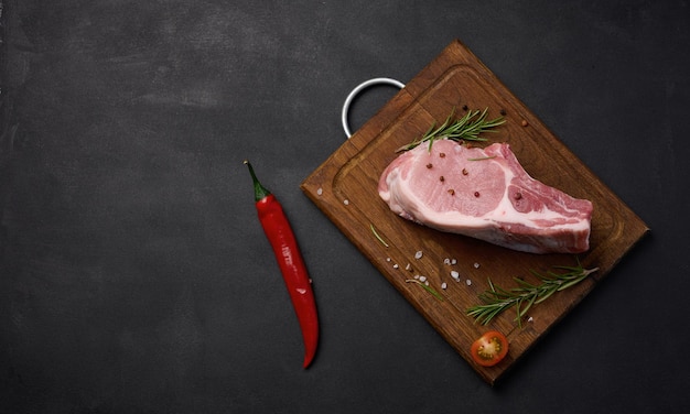 Raw pork tenderloin on the bone and spices on a wooden cutting board Portion for lunch and dinner top view Copy space