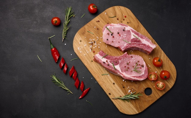 Raw pork tenderloin on the bone and spices on a wooden cutting board Portion for lunch and dinner top view