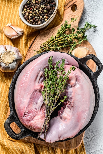 Raw pork tongue with spices and herbs. White background.