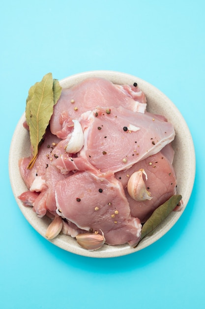 Raw pork with black pepper, garlic and bay leaf on dish