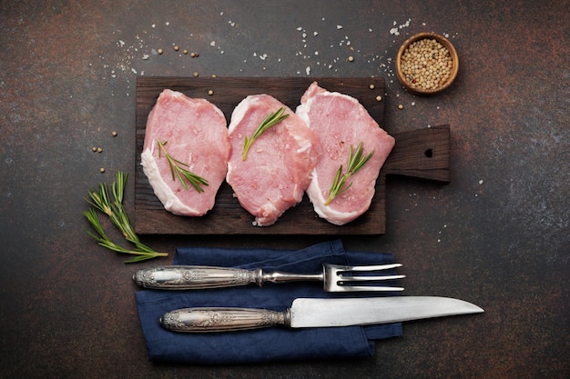 Raw pork on a wooden cutting board on a slate, stone or concrete.   