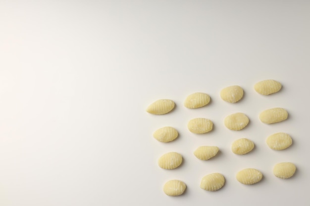 Raw potato gnocchi on white background space for text