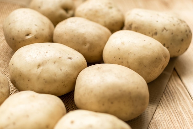 Raw potato tubers on a wooden background