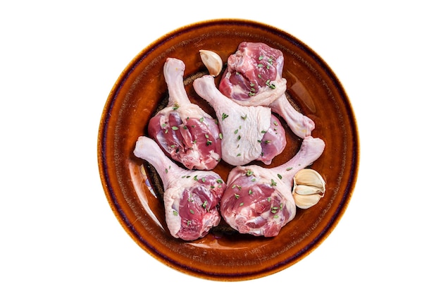 Raw Poultry meat Duck legs drumsticks on a rustic plate with herbs Isolated on white background