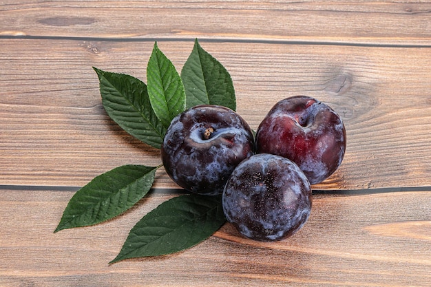 Raw purple plums heap with leaves