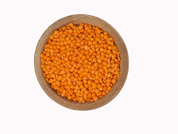 Raw red lentils in wooden bowl on isolated white background