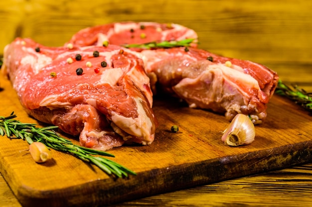 Raw ribeye steak spices rosemary and garlic on wooden cutting board