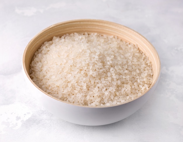 Raw rice in a bamboo bowl on a concrete