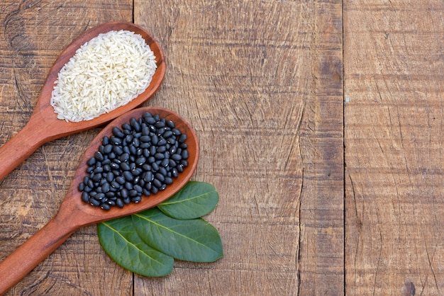 Raw rice and beans, on wooden spoon with bay leaves