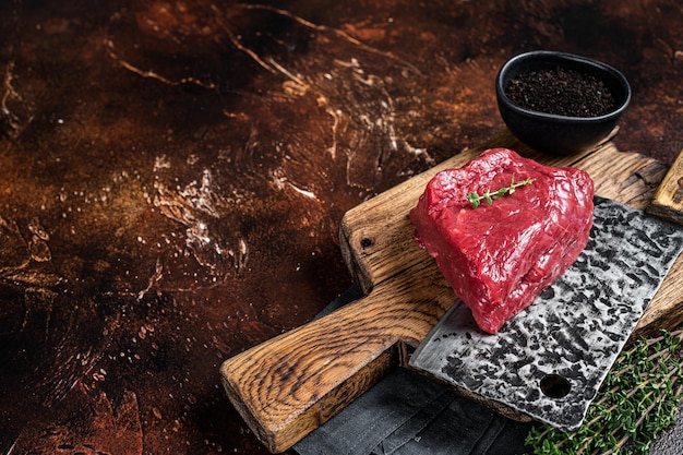 Photo raw rump steak on a butcher cutting board dark background top view copy space