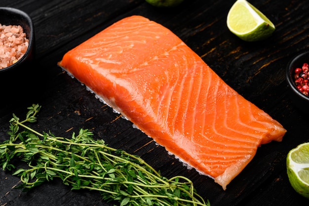 Raw salmon fillet fish meat set, with herbs, on black wooden table background