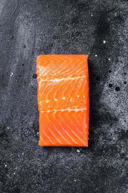 Raw salmon fillet steaks on kitchen table Black background Top view