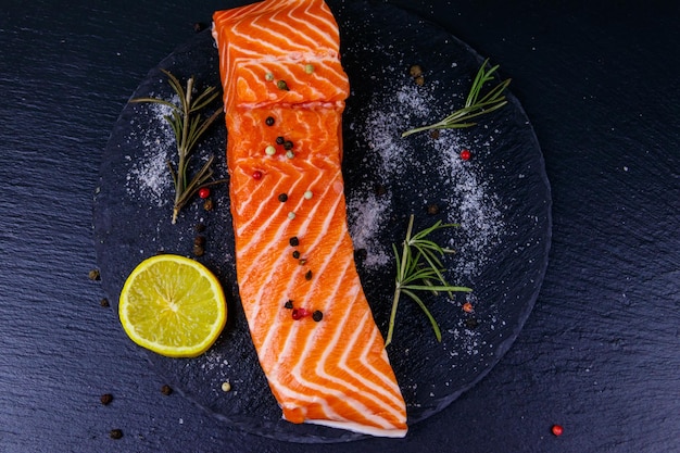 Raw salmon fillet with spices on black slate Top view