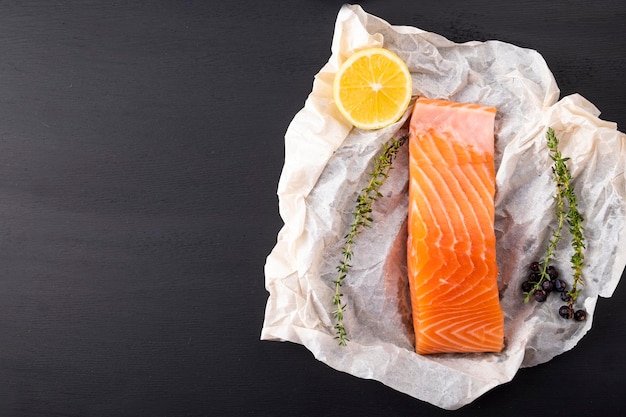 Raw salmon fillet with spices on dark background Top view copy space