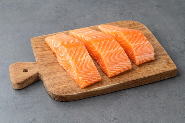 Raw salmon slices with on wooden board over stone background