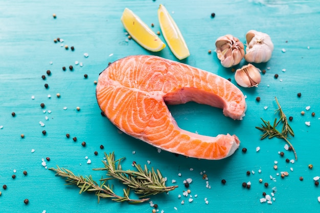 Raw salmon steak on blue background, top view. Healthy food, diet and mediterranean cuisine concept