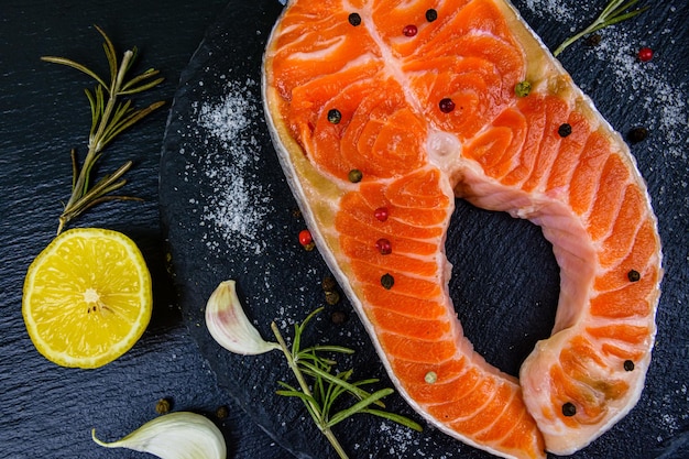 Raw salmon steak and spices on a slate board. Top view