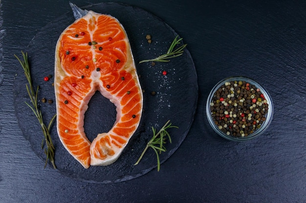 Raw salmon steak with spices on black slate Top view