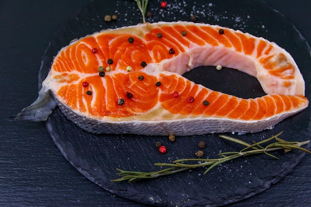 Raw salmon steak with spices on black slate