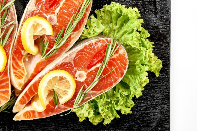 Raw salmon steaks in spices and marinade on blackboard Closeup White background Selective focus