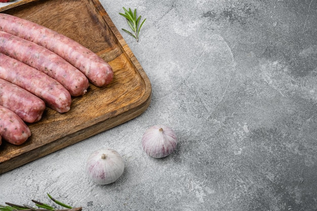 Raw sausage for frying set, on gray stone table background, with copy space for text