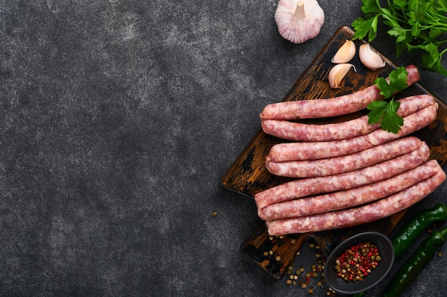 Raw sausages Bratwurst or sausages with ingredients on cutting board with spices on a stone background with copy space Food cooking background Top view