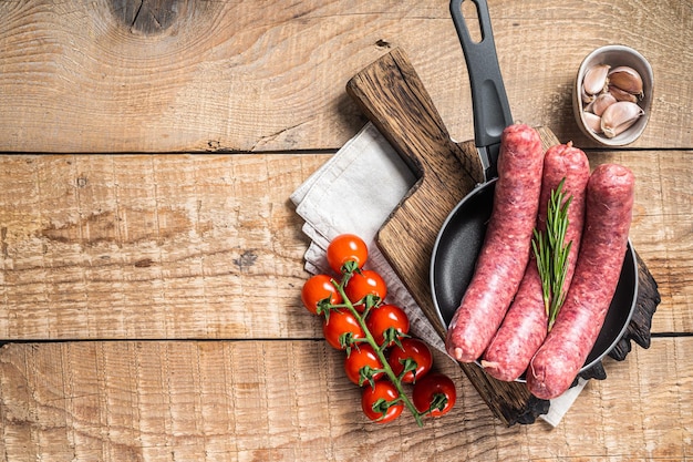 Raw sausages ready for cooking in a skillet uncooked meat Wooden background Top view Copy space